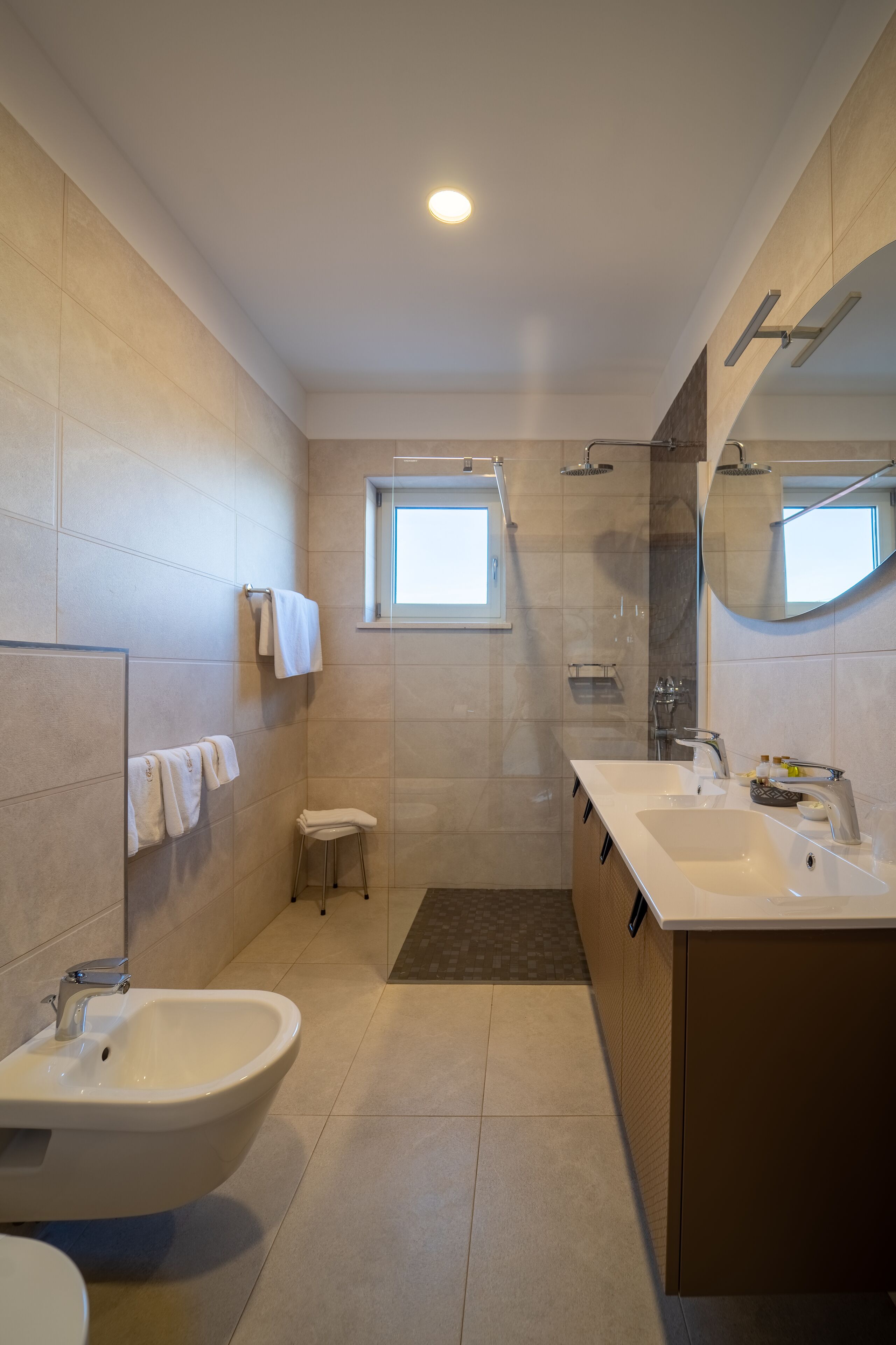 A modern bathroom with a freestanding bathtub, a vanity with a sink, a mirror, and a shower area.
