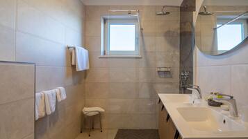 A modern bathroom with a freestanding bathtub, a vanity with a sink, a mirror, and a shower area.