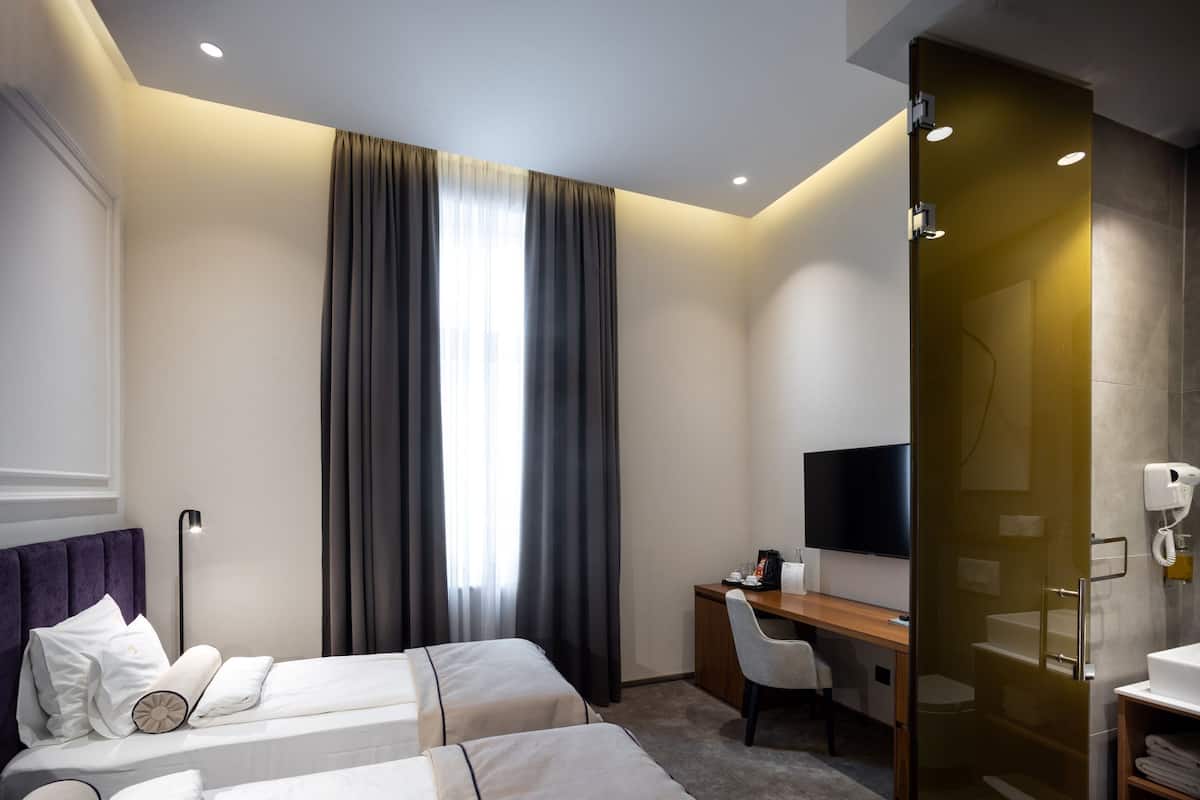 Ein Hotelzimmer mit zwei Betten, einem Schreibtisch, einem Stuhl, einem Fernseher und einem Badezimmer.
