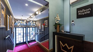 Un vestíbulo de hotel con un mostrador de recepción, una escalera y un gran ventanal.