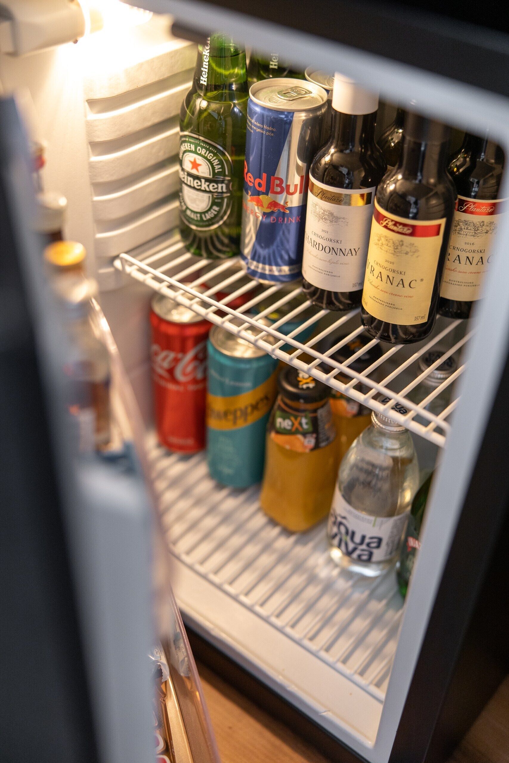 A refrigerator stocked with various beverages including Heineken, Red Bull, and wine bottles.