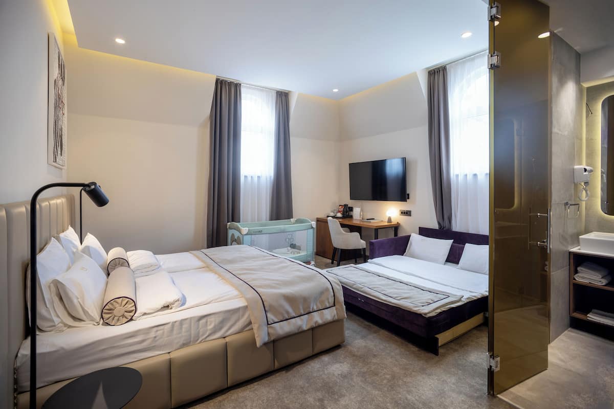 Ein Hotelzimmer mit zwei Betten, einem Schreibtisch, einem Fernseher und einer Dusche.