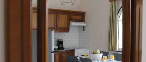 Ett kök med träskåp, ett matbord med stolar och en hängande lampa.