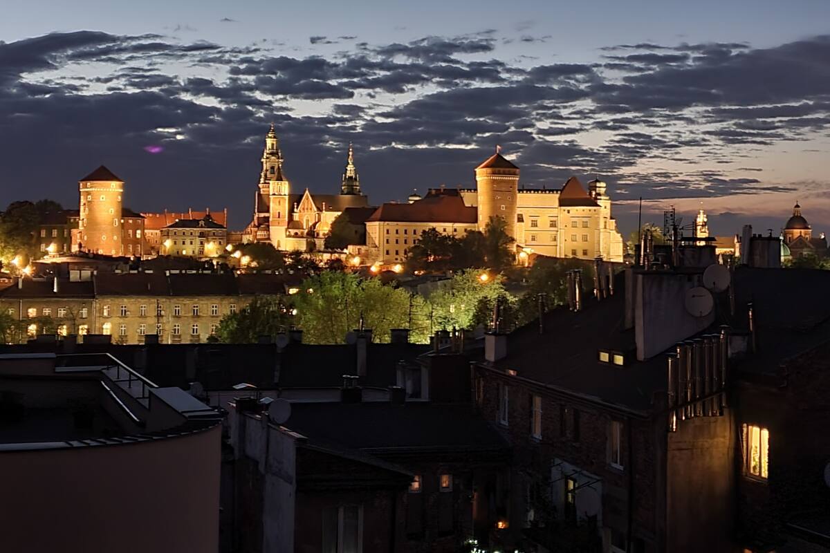 A historic cityscape with illuminated buildings and a prominent castle at dusk.