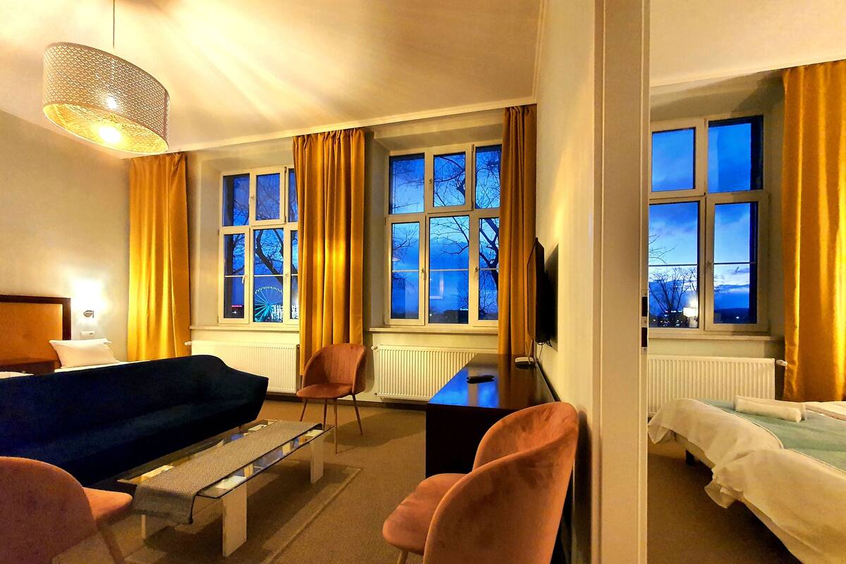 A hotel room with a bed, a desk, a chair, a sofa, and a TV.