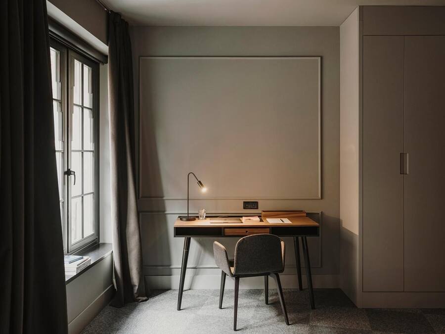 A study room with a desk, chair, lamp, and wardrobe.
