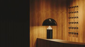 Welcome to our reception area, featuring a curved counter, a stylish lamp, and a unique geometric patterned window.