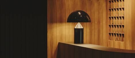 A wooden reception desk with a black lamp and a geometric patterned window.