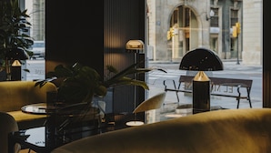 A modern interior with a sofa, a table, and a lamp. - El Môderne Hotel Urban & Unique (Gijon)