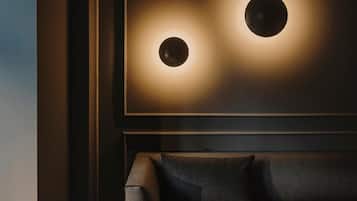 Una habitación moderna con una pared oscura y una obra de arte enmarcada que presenta dos fuentes de luz circulares.
