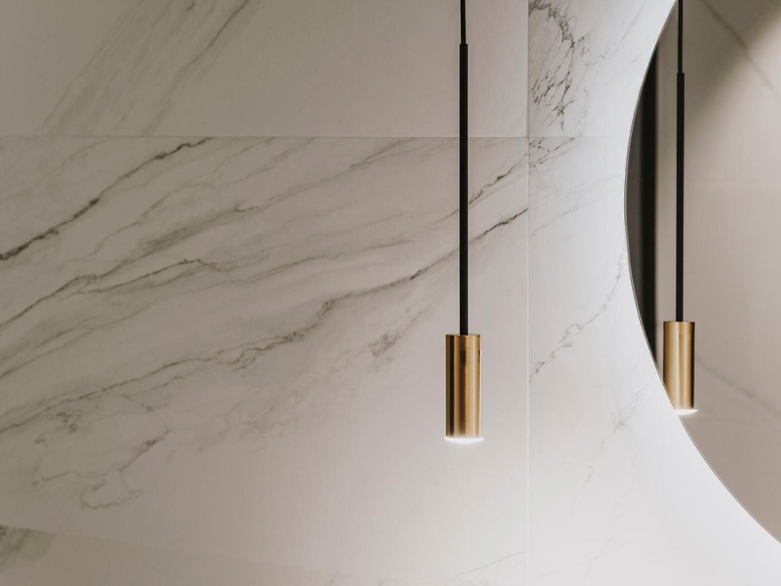 A modern ceiling with a marble pattern and two pendant lights with gold-colored bases.