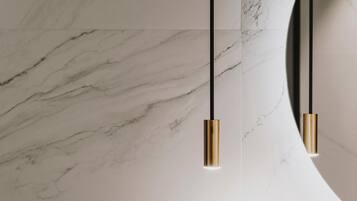 A modern ceiling with a marble pattern and two pendant lights with gold-colored bases.