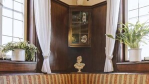 A room with a dark wooden door, a bust sculpture, and two potted plants. - Hotel Filoxenia (Stuttgart)