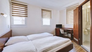 A bedroom with two beds, a desk, and a TV. - Hotel Filoxenia (Stuttgart)
