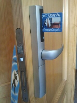A door with a silver handle and a magnetic card reader. - Hostal Arneva (Orihuela)