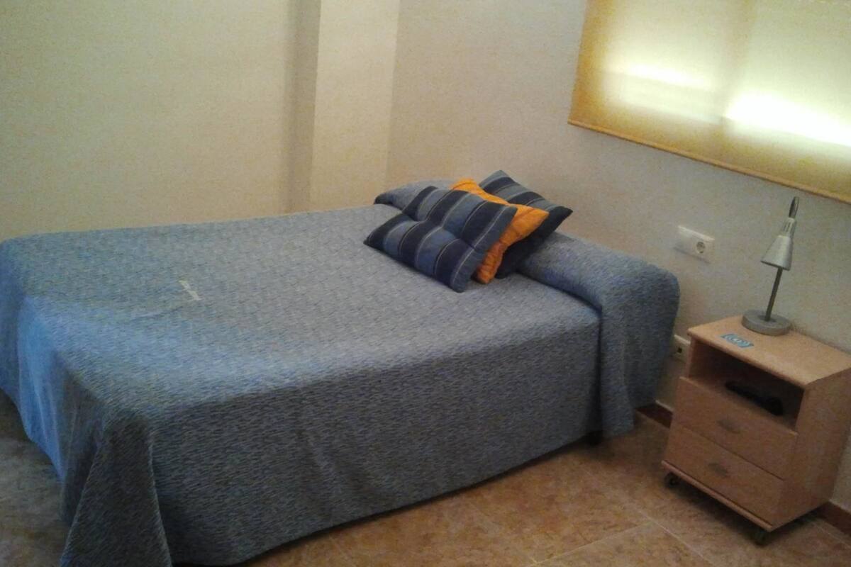 A bedroom with a bed, a nightstand, and a lamp.