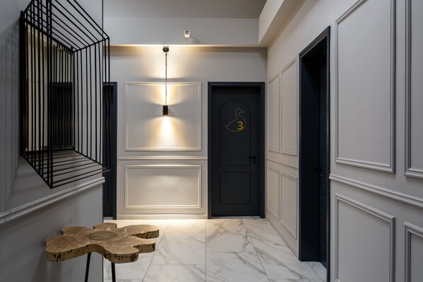 Experience the elegant atmosphere of this beautifully designed hallway, featuring a warm glow from the ceiling light fixture, a wooden table, and a classic marble floor.