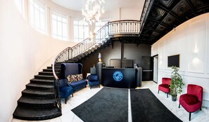 Step into the grand lobby, featuring a reception desk, comfortable seating areas, and a beautiful staircase.