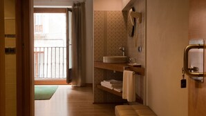 A bathroom with a wooden bench, a sink, and a towel rack. - Hospederia Chapitel (Estella)