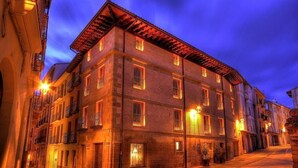 A multi-story building with a brick facade, multiple windows, and balconies. - Hospederia Chapitel (Estella)