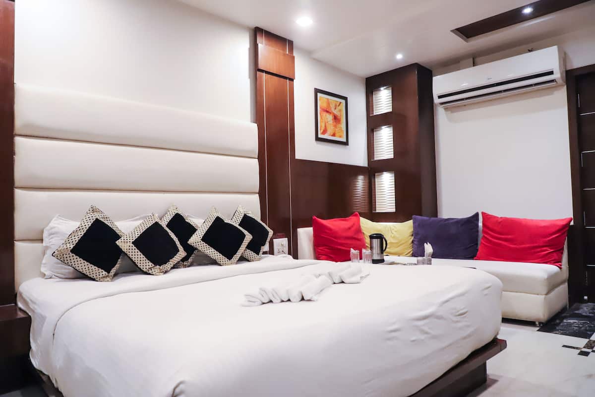 Une chambre d’hôtel avec un grand lit, un canapé et un appareil de climatisation.