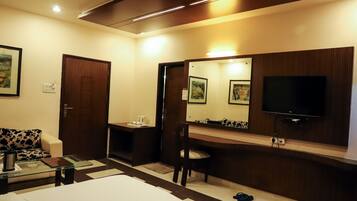 A hotel room with a bed, a desk, a chair, a TV, a mirror, and a door.