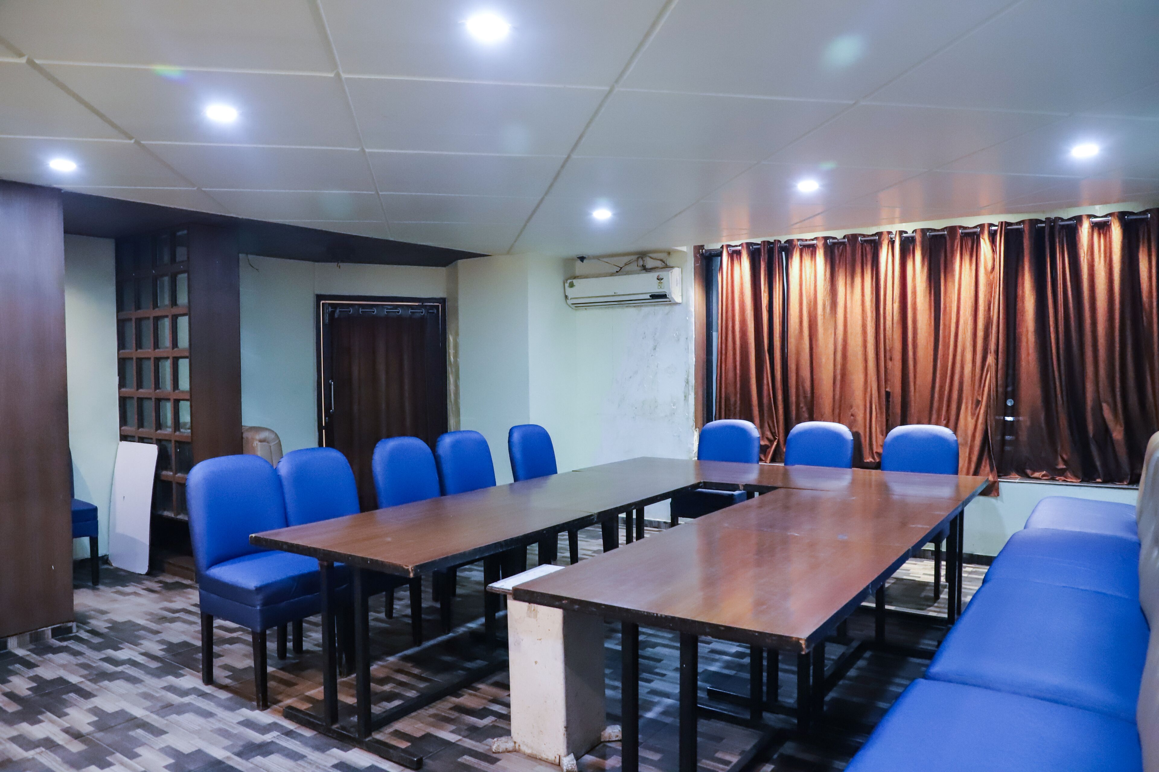 Un salón de conferencias con una larga mesa, sillas azules y un sofá marrón.