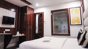 Une chambre d’hôtel équipée d’un lit, d’une télévision, d’un bureau et d’une salle de bain visible à travers une porte en verre.
