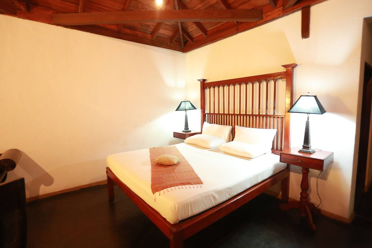 A bedroom with a wooden bed, two bedside lamps, and a wooden headboard.