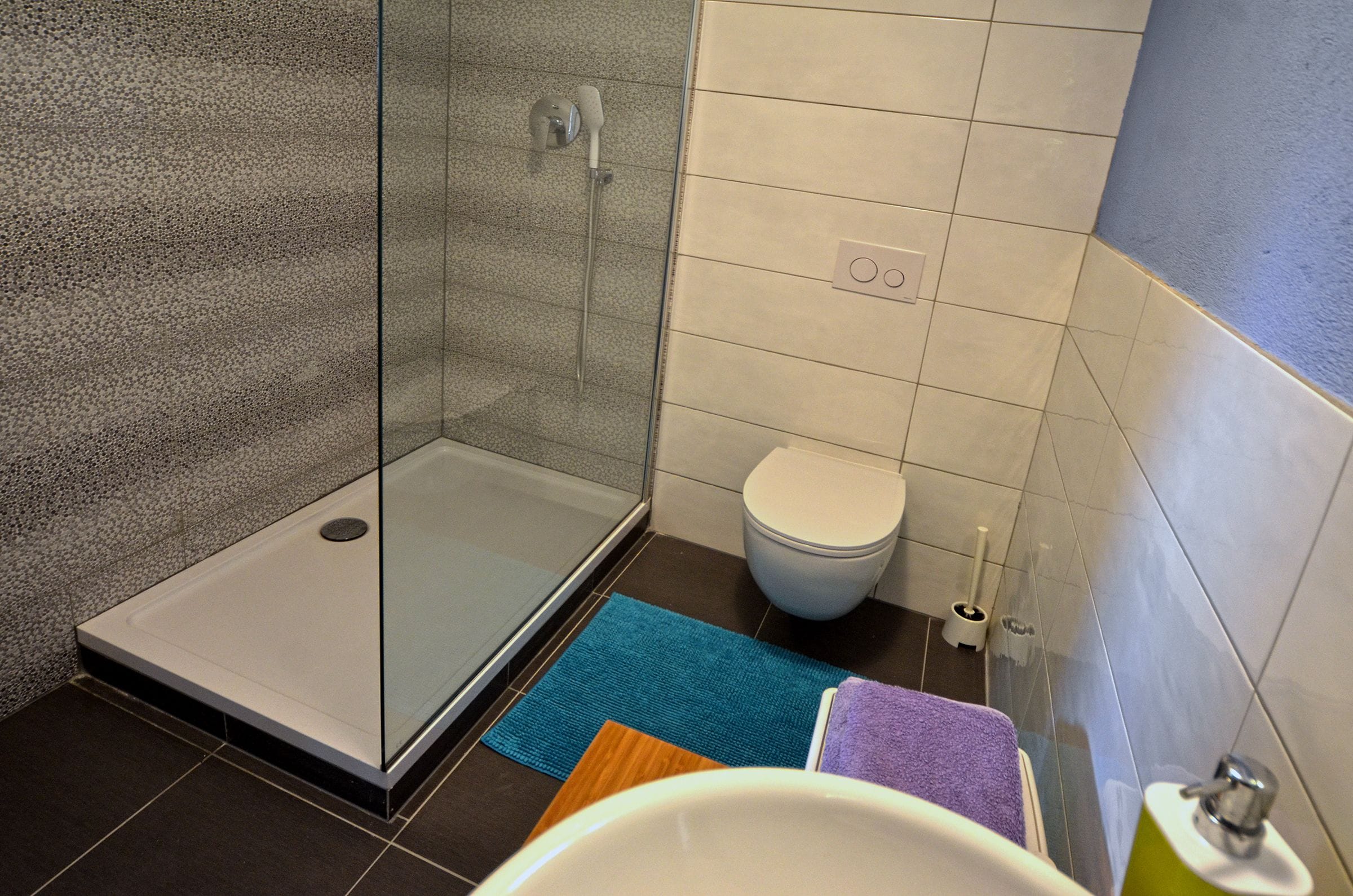 A bathroom with a glass shower enclosure, a toilet, and a sink area.