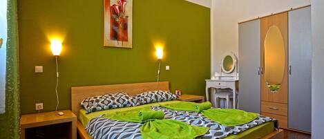 A bedroom with a bed, two bedside tables, a nightstand, a wardrobe, and a painting on the wall.