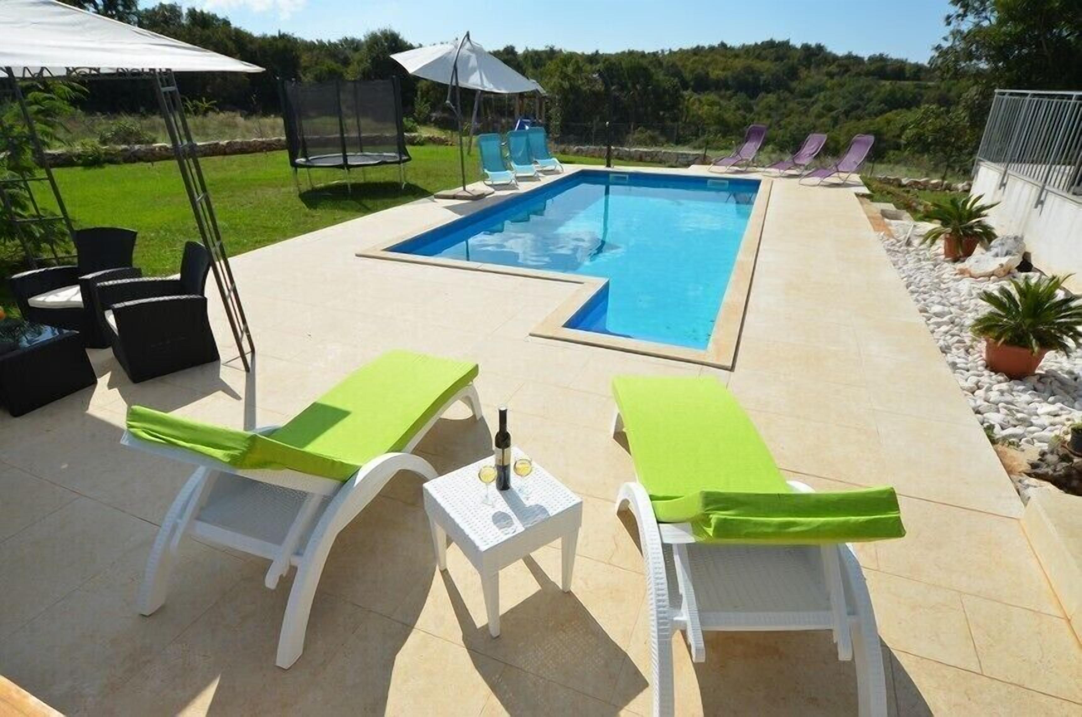 Une piscine avec des chaises longues et une table où sont servis des boissons.