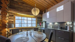 Interior acogedor de una cabaña de troncos con comedor y cocina.