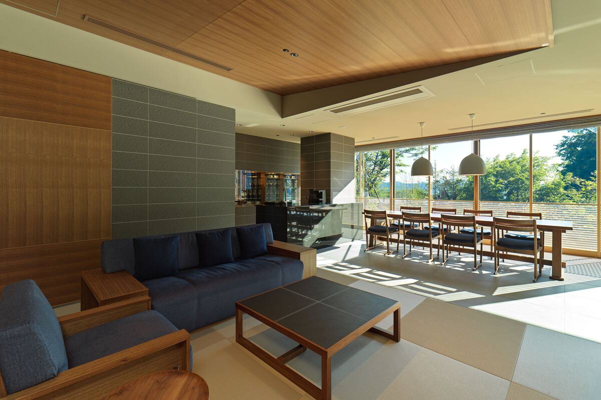 A modern living room with a sofa, coffee table, and dining area with chairs.