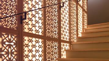 Un escalier avec des marches en bois et un panneau décoratif en bois orné de motifs complexes découpés.
