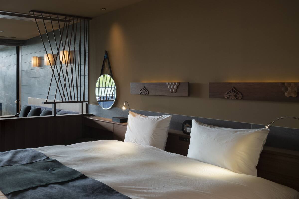 A modern hotel room with a large bed, a desk, and a window with a view.