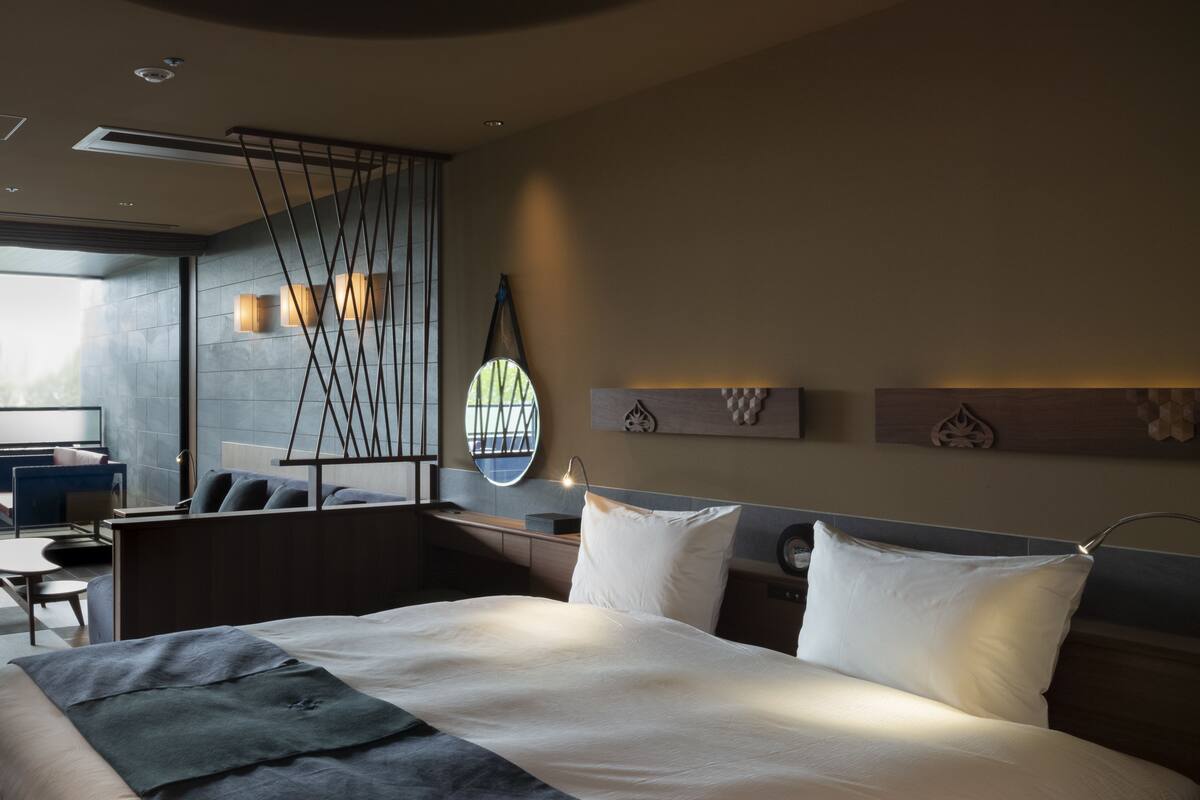 A modern hotel room with a large bed, a desk, and a view of the outdoors.