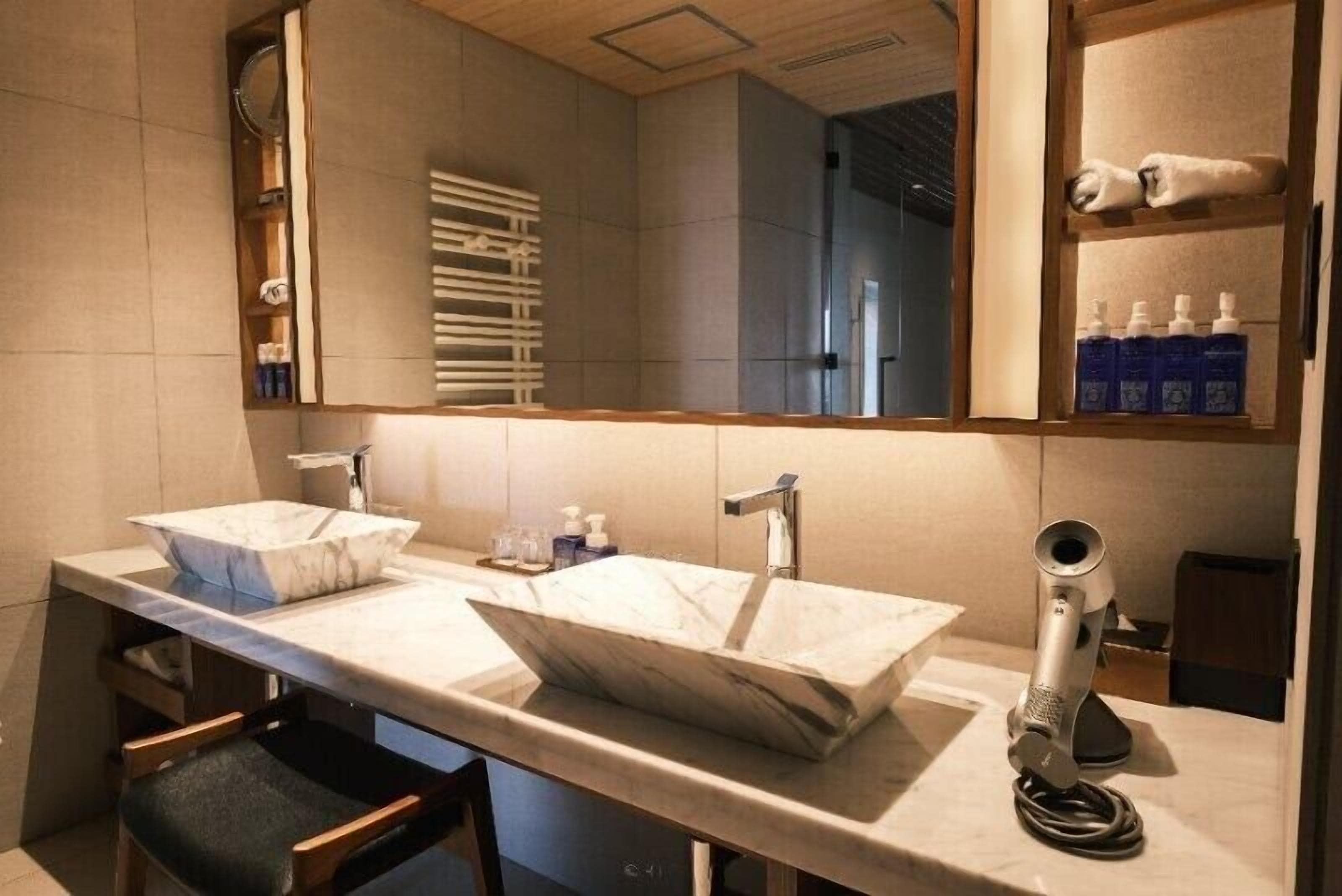 Une salle de bain moderne avec deux lavabos, un grand miroir et un porte-serviettes.