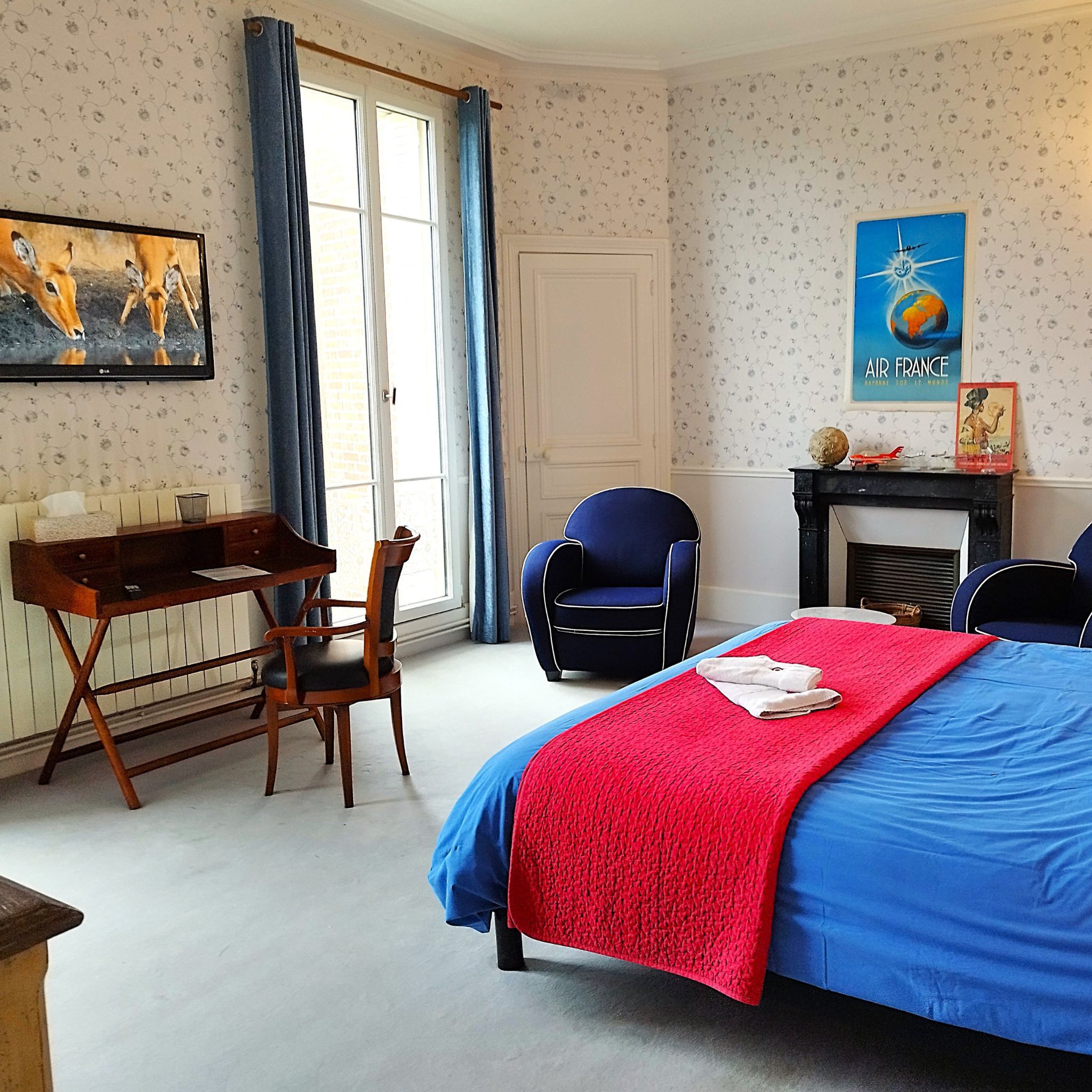 Ein Schlafzimmer mit einem Bett, einem Schreibtisch, einem Sessel, einem Kamin und einem Bild an der Wand.