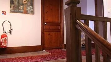 A staircase with a wooden handrail and red carpeted steps leading to a wooden door.