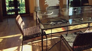 A dining area with a glass table and metal chairs, large windows with a view of greenery, and a fireplace with a decorative mantel. - Les Tourelles de Thun (Meulan-en-Yvelines)
