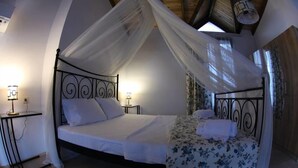 A four-poster bed with a canopy, bedside tables with lamps, and floral bedspread. - Karaburun Mimoza Apart Hotel (Karaburun)