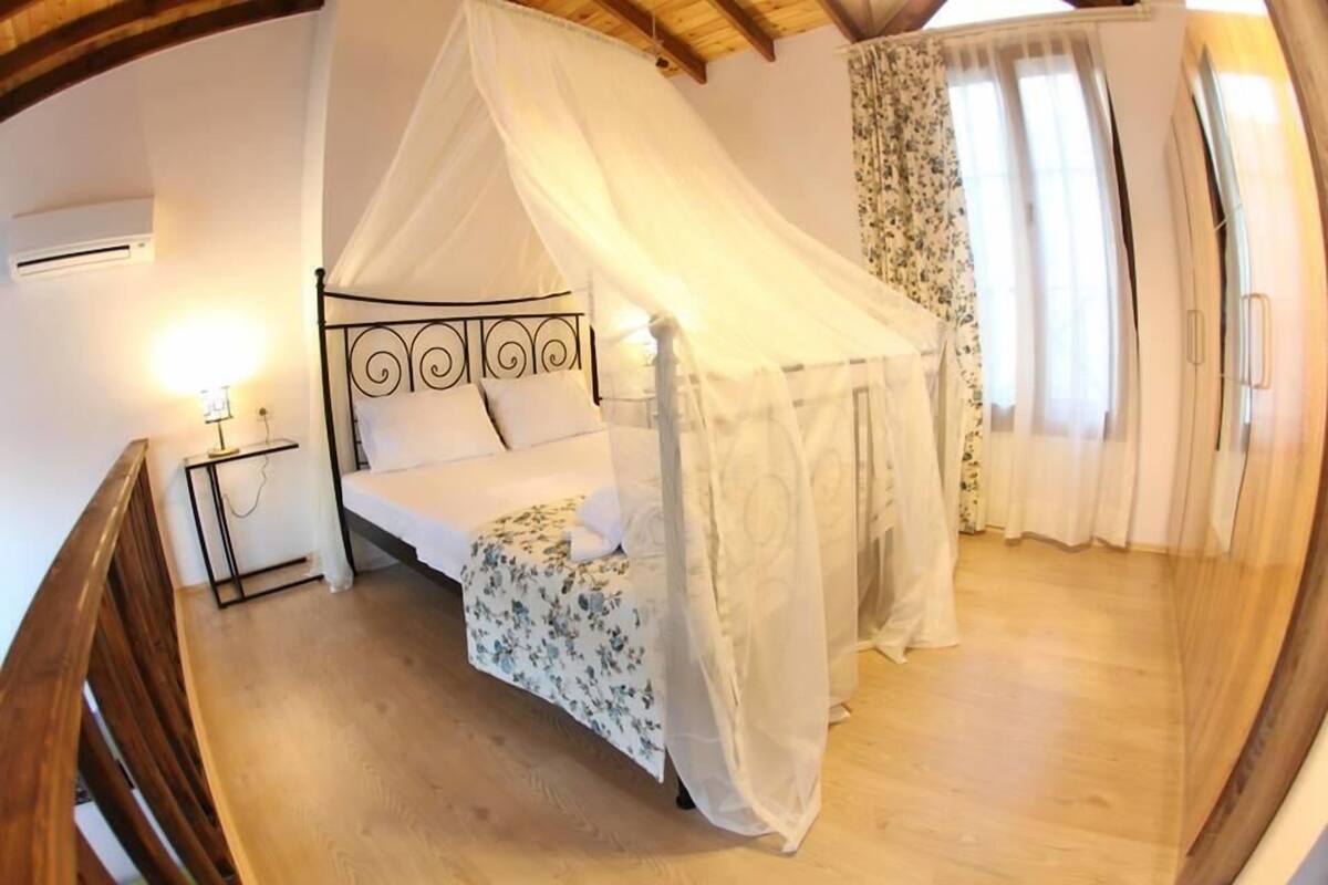 Une chambre à coucher avec un lit à baldaquin, une table de chevet et une commode.