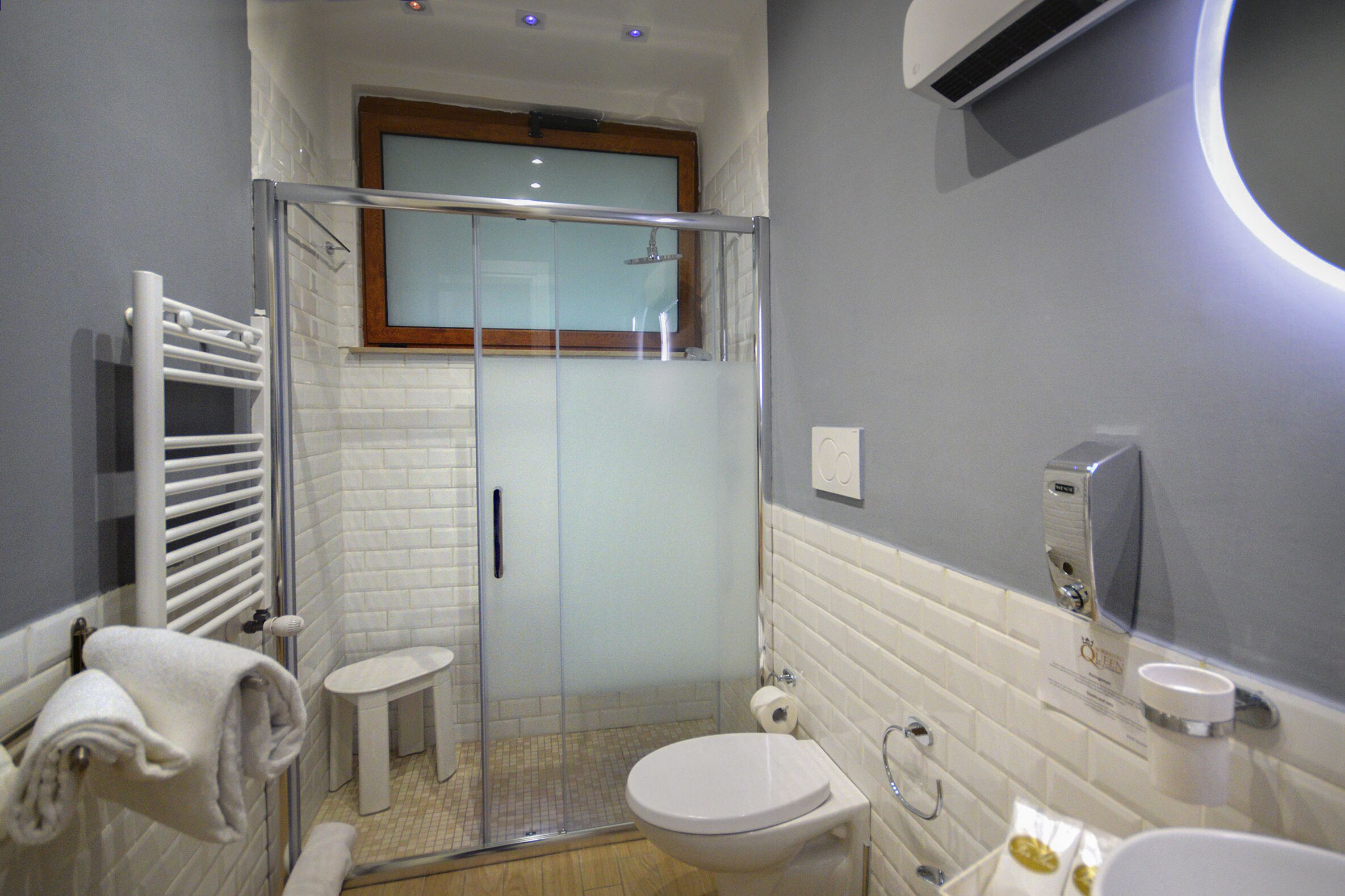 A modern bathroom with a glass-enclosed shower, a white toilet, and a sink with a soap dispenser.