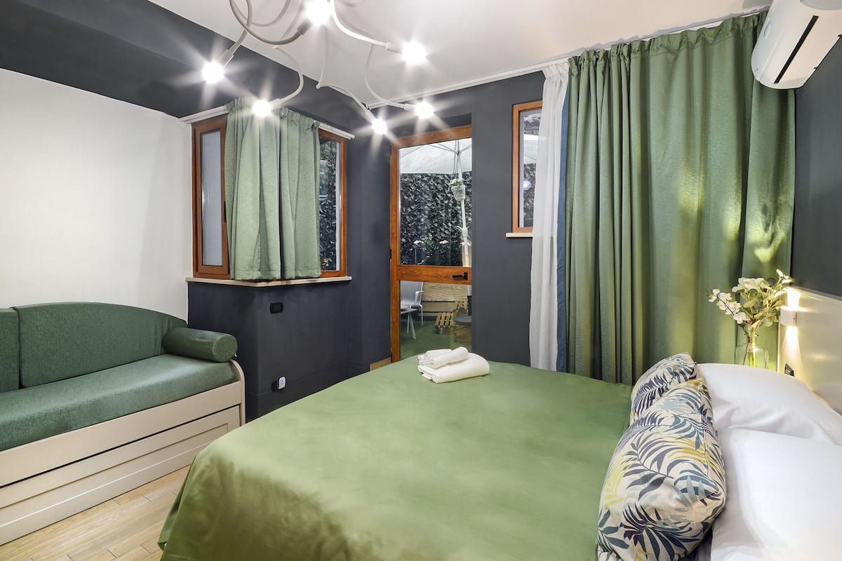 Une pièce avec un lit, un canapé et une fenêtre avec des rideaux.