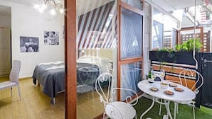 Une chambre moderne avec un lit, une chaise et une table sur laquelle se trouvent de la nourriture et des boissons.