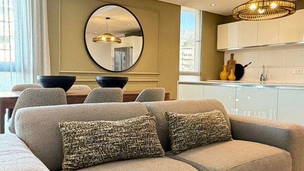 A modern living room with a sofa, a dining table, and a kitchen area. - Warwick 501 (Cape Town)