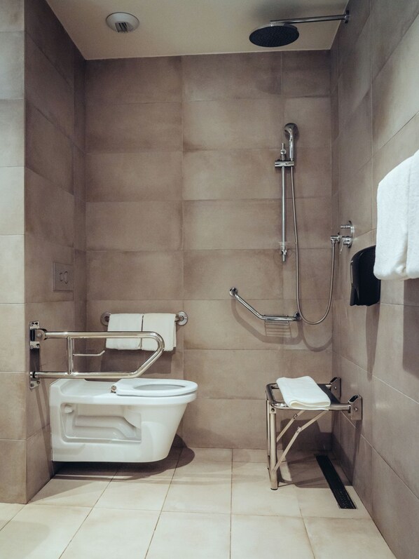 A bathroom with a shower, a toilet, and a grab bar.