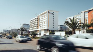 Een hotel met meerdere verdiepingen, een opvallend bord en een parkeerplaats met auto's.