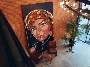 A modern interior with a large mural, leather seating, and a potted plant. - ONOMO Hotel Casablanca Sidi Maarouf (Casablanca)